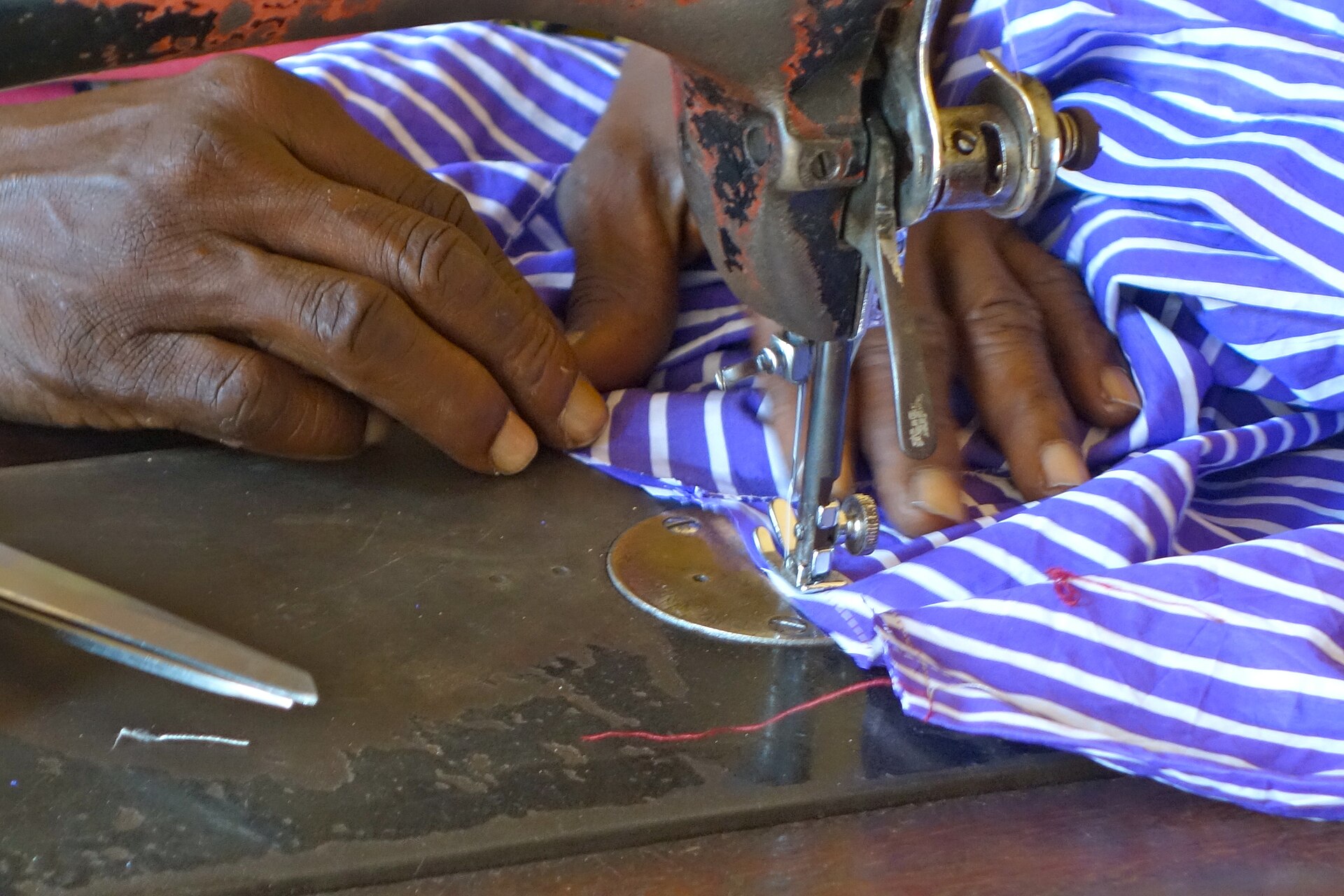 Tailors finishing a garment at the worktable